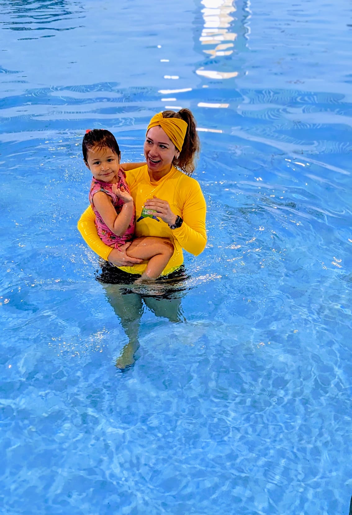 ISR-certified instructor supporting a young child during a one-on-one lesson in the pool.